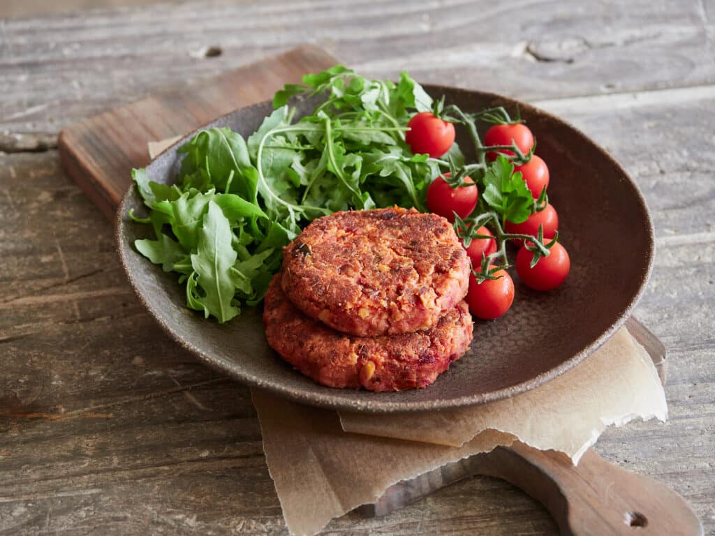 homemade veggie burgers served with rocket and cherry tomatoes